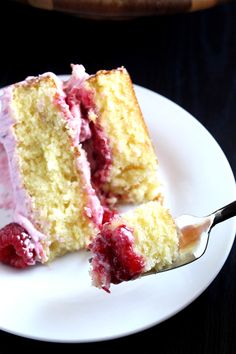 a piece of cake with raspberry icing on a plate next to a fork