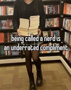 a girl standing in front of a bookshelf holding stacks of books