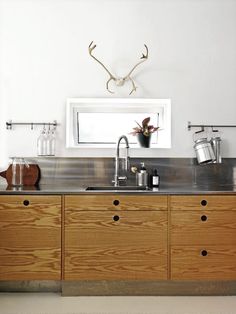 a kitchen with wooden cabinets and stainless steel counter tops is pictured in this image, there are antlers on the wall above the sink