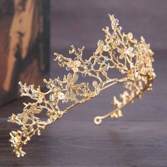 a gold tiara on a table next to a box with an image in the background