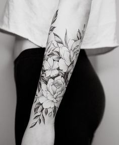 a woman's arm with flowers and leaves tattooed on her left arm, in black and white