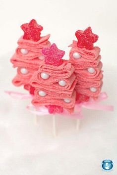 three small pink christmas trees on top of each other with red bows and white pearls