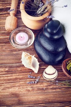 various spa items on wooden table with candles and flowers in vases next to them