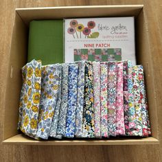 a box filled with lots of different types of fabric on top of a wooden table