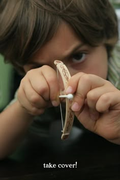 a young boy holding up a fake banana to his face with the caption take cover