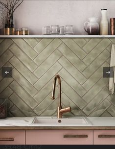 a kitchen sink with copper faucet next to a counter top and pink cabinets