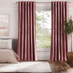 a bedroom with pink curtains and a bed in front of a window that has a potted plant next to it