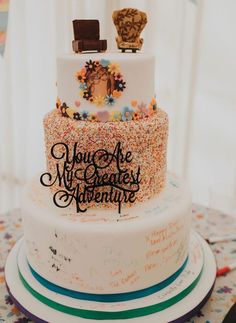 there is a three layer cake that has confetti on the top and writing on the bottom