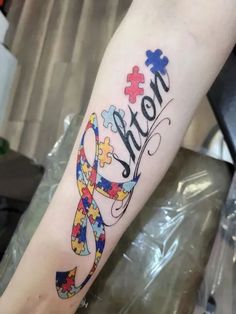 a person with a tattoo on their arm that says mom and has puzzle pieces all over it