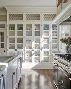 a kitchen with white cabinets and stainless steel stove top oven in front of glass doors