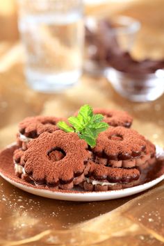 some cookies are on a white plate with green leaves