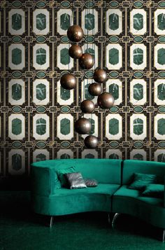 a green couch sitting in front of a wall covered with mirrors and balls on it