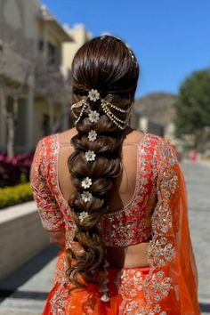 a woman in an orange dress with long hair and pearls on her head is standing outside