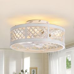 a white ceiling light hanging from the ceiling in a living room with windows and curtains