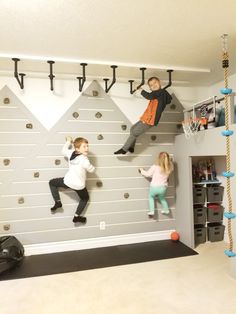 two children climbing up the side of a wall with basketball hoopes on it,