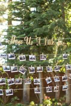 there are many pictures hanging on the clothes line with string attached to it and some trees in the background