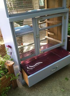 a large bird cage sitting on top of a wooden table next to a planter