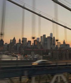 a car is driving on the bridge in front of a cityscape at sunset