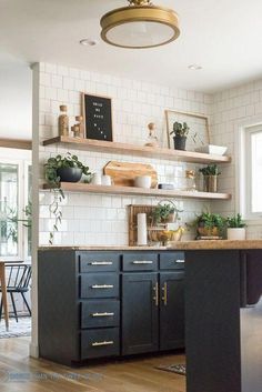 a kitchen with black cabinets and white subway backsplash, gold trimmings