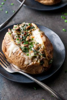 a baked potato covered in cheese and herbs on a plate with a fork next to it