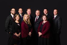 a group of people standing next to each other in front of a black background wearing suits and ties