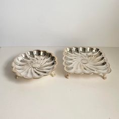 two silver dishes sitting next to each other on a table