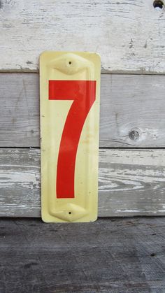 a yellow and red number seven sign on a wooden wall