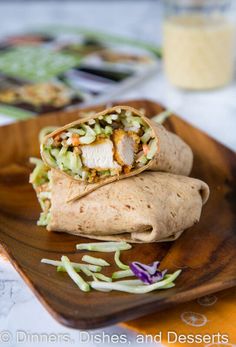 a burrito on a wooden plate next to a glass of orange juice and other food items