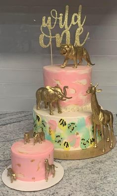 three tiered cake with gold elephants and giraffes on top