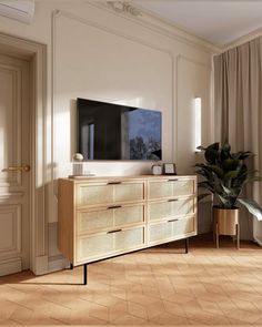 a living room scene with focus on the dresser and large screen tv in the corner