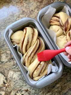 two tins filled with pastries sitting on top of a counter next to a red brush