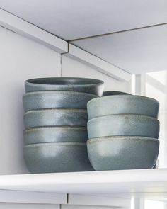 several bowls are stacked on top of each other in the kitchen shelf, and one is empty