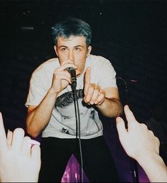 a man holding a microphone up to his mouth while standing in front of other people