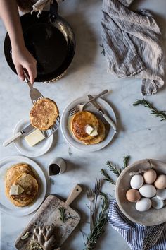 two plates with pancakes and eggs on them sitting on a table next to utensils