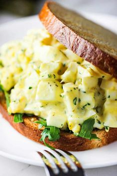 an egg salad sandwich on a plate with a fork