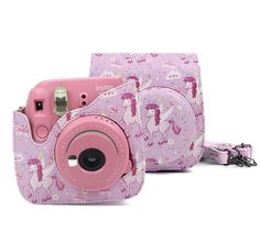 a pink digital camera sitting on top of a white table next to a bag with an unicorn pattern