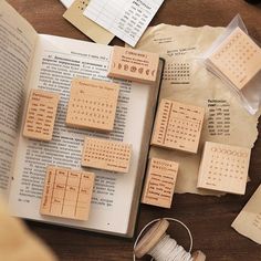 several pieces of wood sitting on top of an open book next to spools of thread