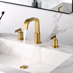 two faucets running water in a bathroom sink with marble counter top and mirror