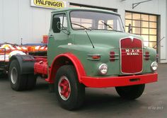 a green and red truck parked in front of a building