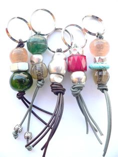 several different colored beads are attached to some metal rings and leather cords with silver balls on them