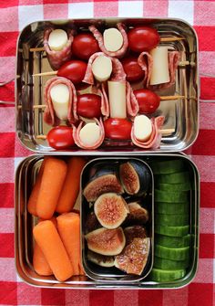 two metal trays filled with food on top of a red and white checkered table cloth