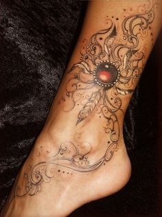 a woman's foot with tattoos on it and a red eye in the center