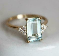 an aquamarinee and diamond ring on a white surface