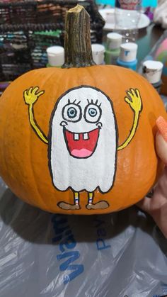 a person holding up a painted pumpkin with an image of a cartoon character on it