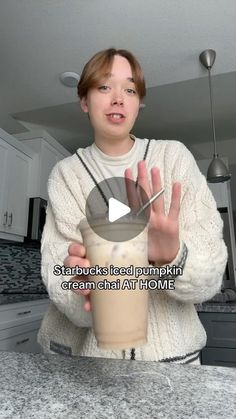 a woman holding a drink in her hand with the caption starbucks iced pumpkin cream at home