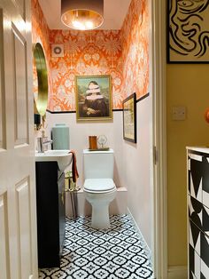 a white toilet sitting inside of a bathroom next to a sink under a light fixture