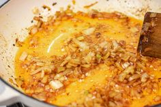 the food is being cooked in the pan on the stove top with a wooden spatula