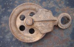 an old rusted metal object with holes in it's center and two wheels