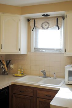 a kitchen with white cabinets and brown counter tops is seen in this image, the window above the sink looks out onto the outside