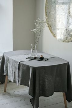 a table with a vase and some flowers on it in front of a round mirror